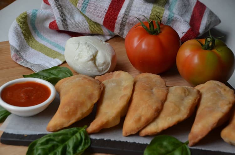Half-moon filled pizza with chicken, tomato sauce and fresh herbs